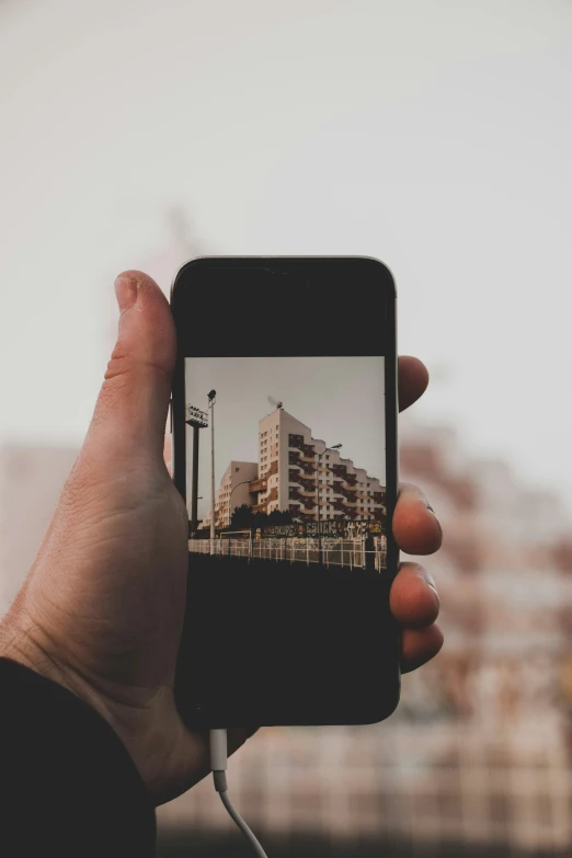 a hand holding an iphone with a building in the background