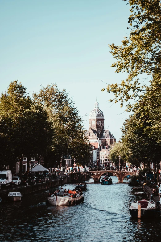 a canal with boats and people sitting at the curb