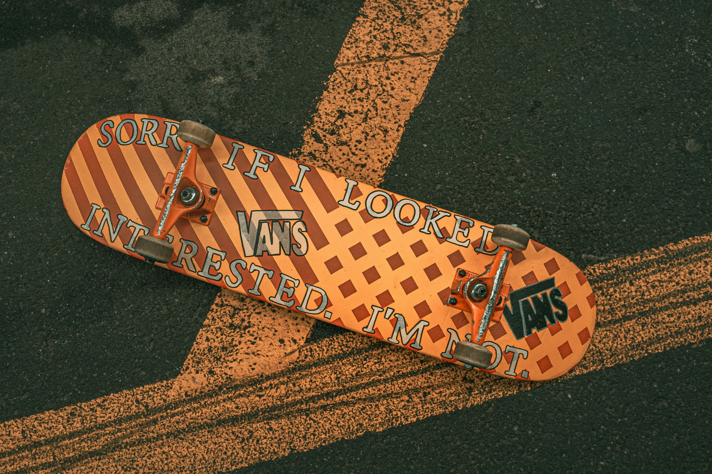 an orange skateboard laying on top of the road