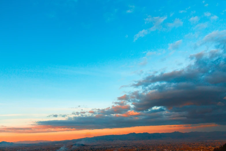 a couple people watching the sun set over a large city