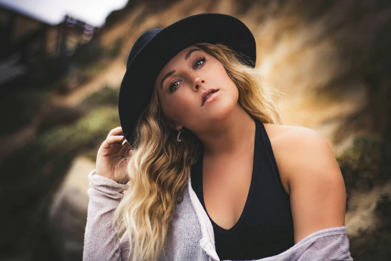 a woman in a hat is posing near rocks