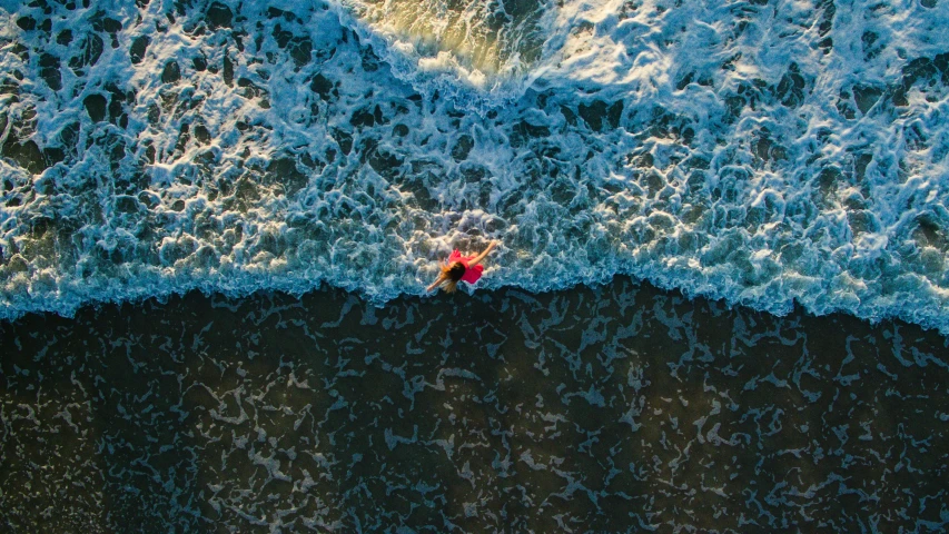 two people ride surfboards over an ocean wave