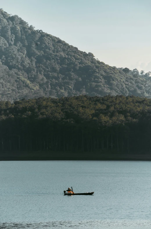 boat with oar on lake in front of trees and hills