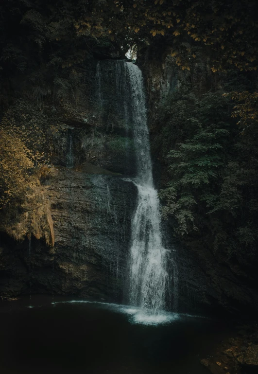 a beautiful waterfall on the side of the road in the woods