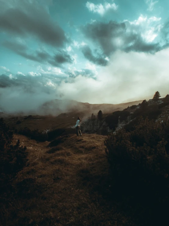 a person on a grassy hill overlooking hills