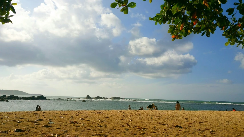 people on the beach by the ocean under clouds