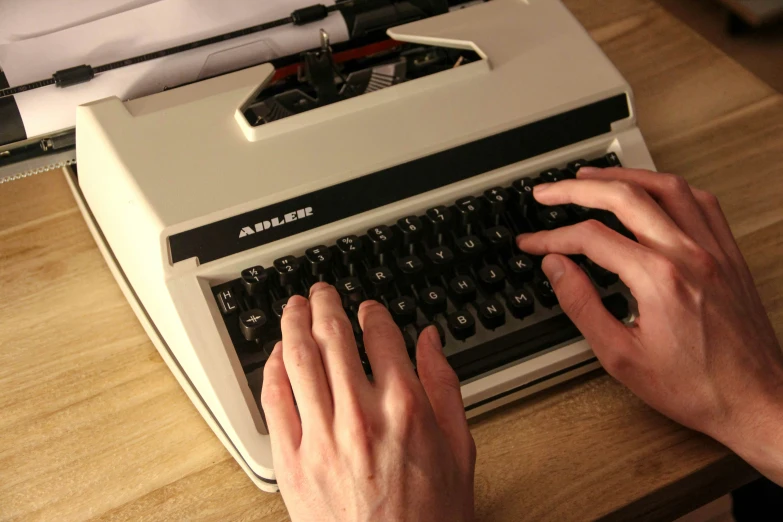 person typing on old - fashioned typewriter on wooden table