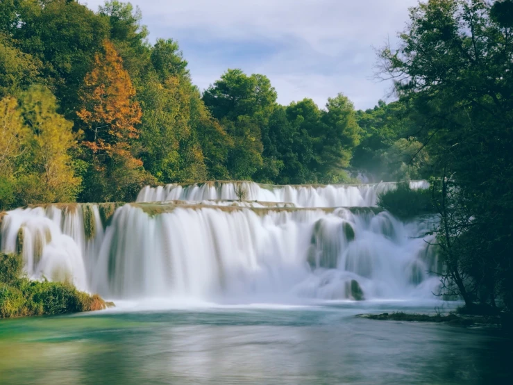 a large waterfall filled with water surrounded by trees