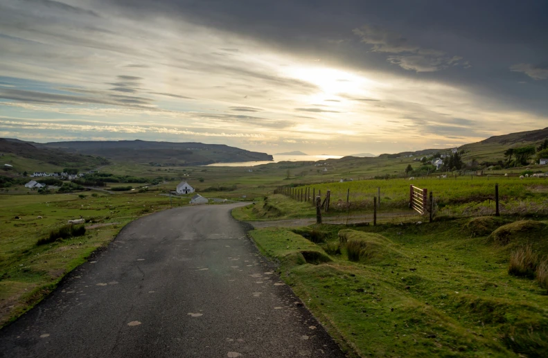 a paved road in the middle of some green grassy land