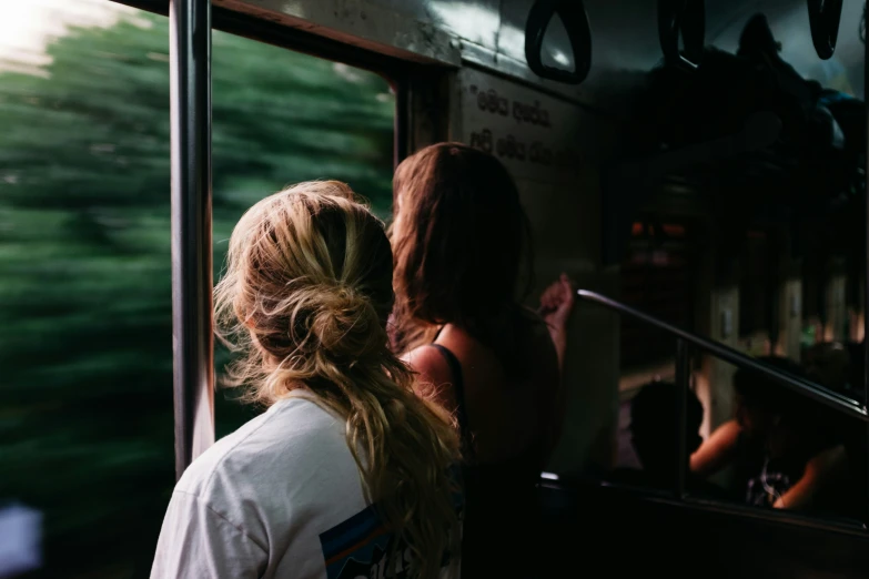 two people look out a train window at the trees