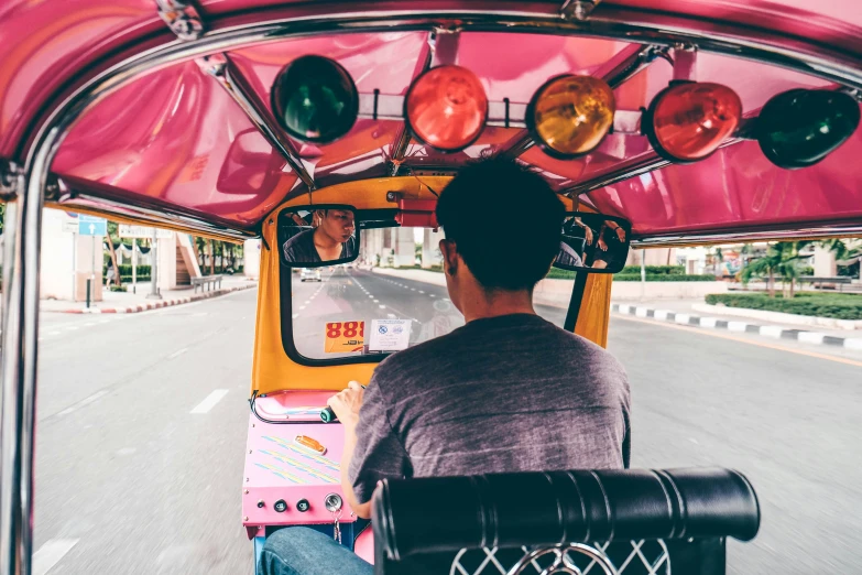 a guy driving with a pink tuk tuk