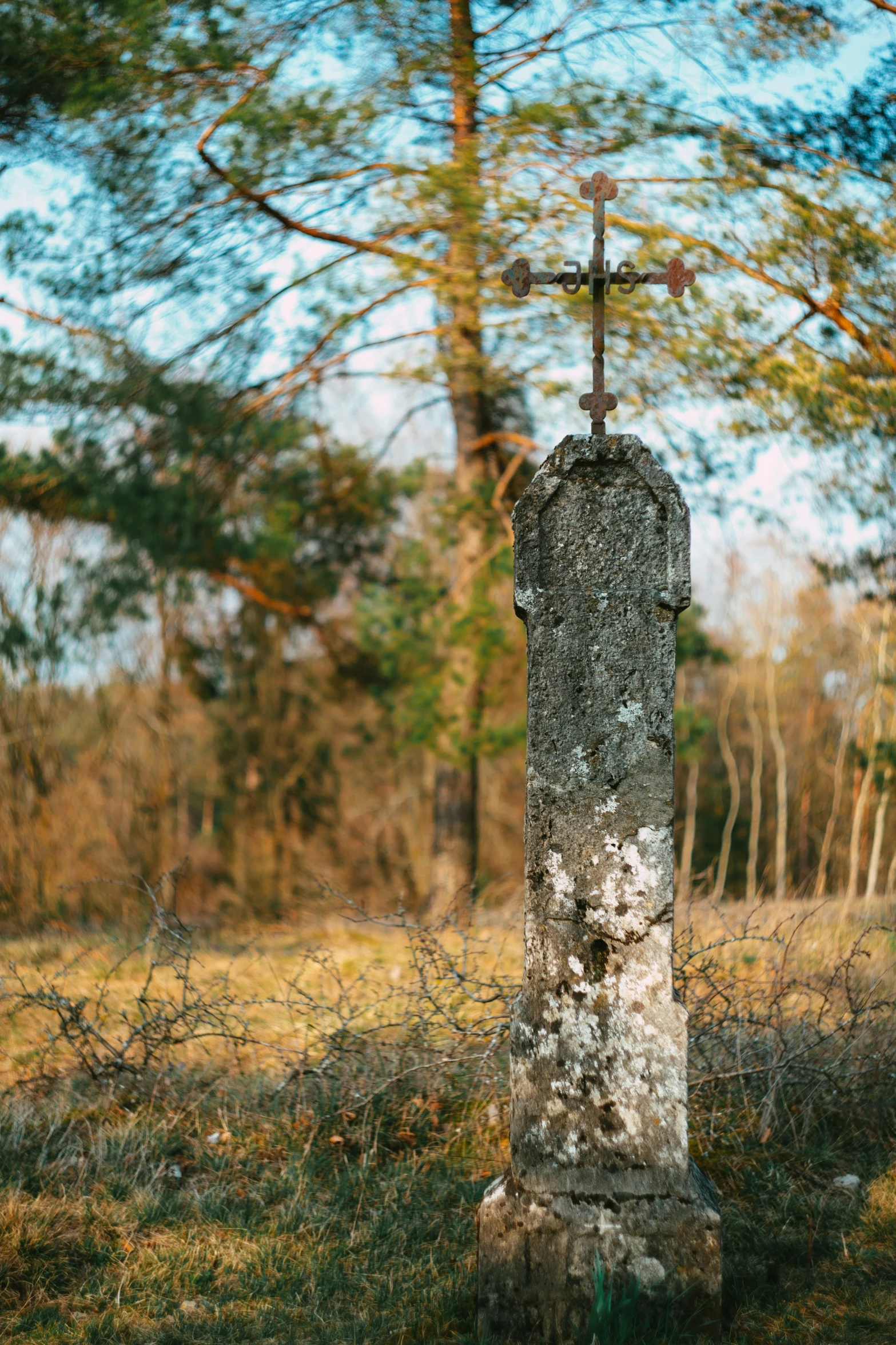 an old stone cross with a wooden cross in a forest