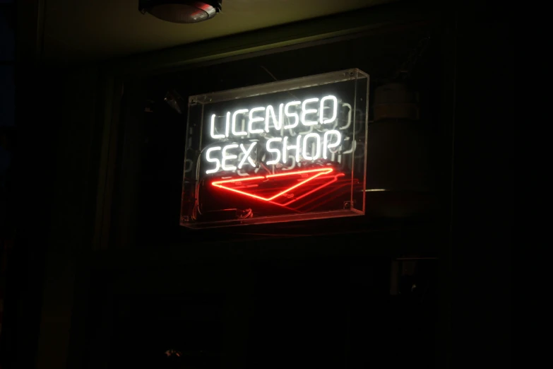 neon sign hanging from a building with the text banned sex shop