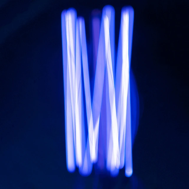 four long white lights in motion against a black background