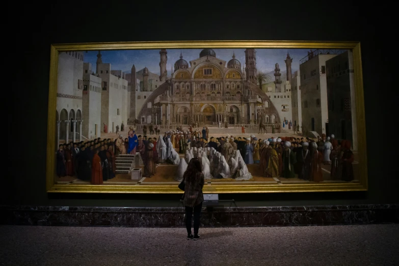 a woman standing in front of a large painting of people and buildings