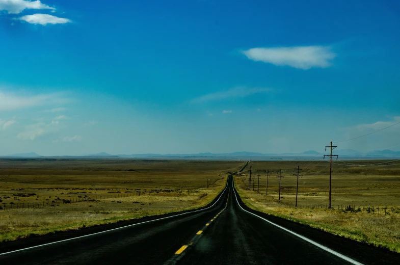 a road in the middle of a desert, with a lone vehicle at the top