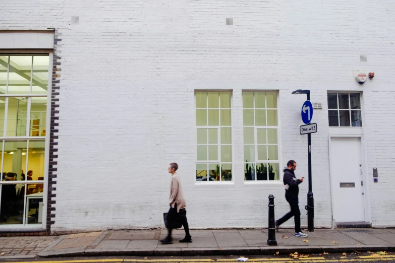 two people walking by a tall white building