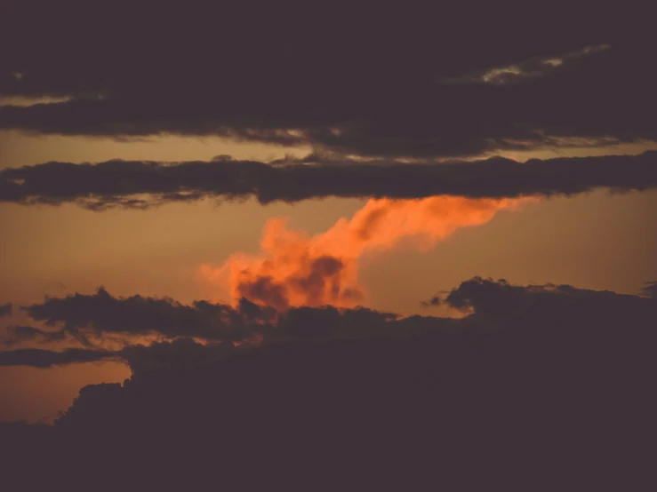 an airplane flying past some clouds and the setting sun