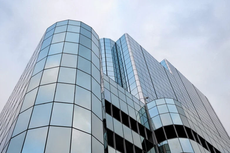 the reflection of a clock on the glass windows of a building