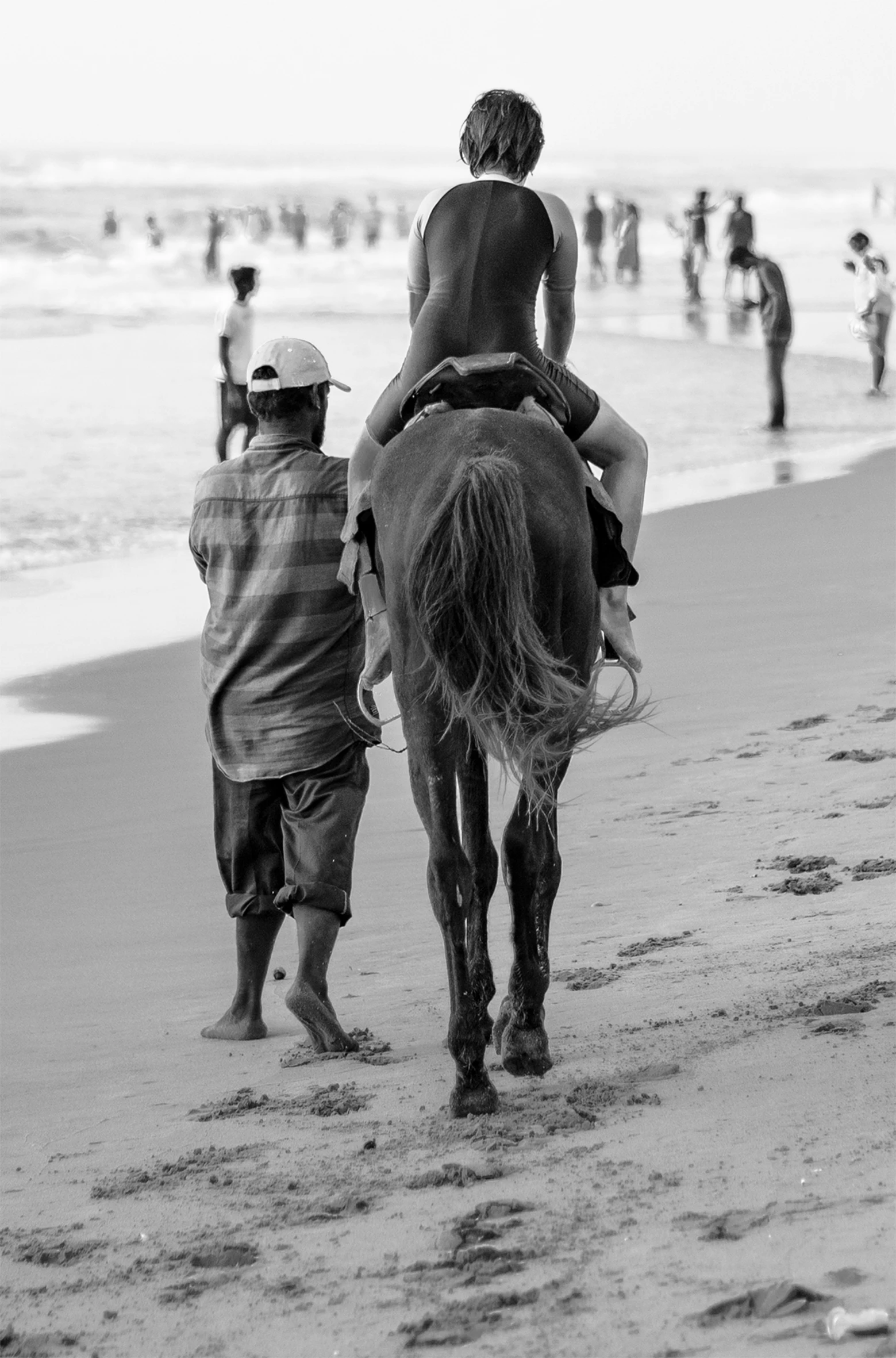 a  and woman riding a horse at the beach