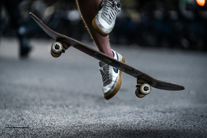 a person wearing tennis shoes does tricks on a skateboard