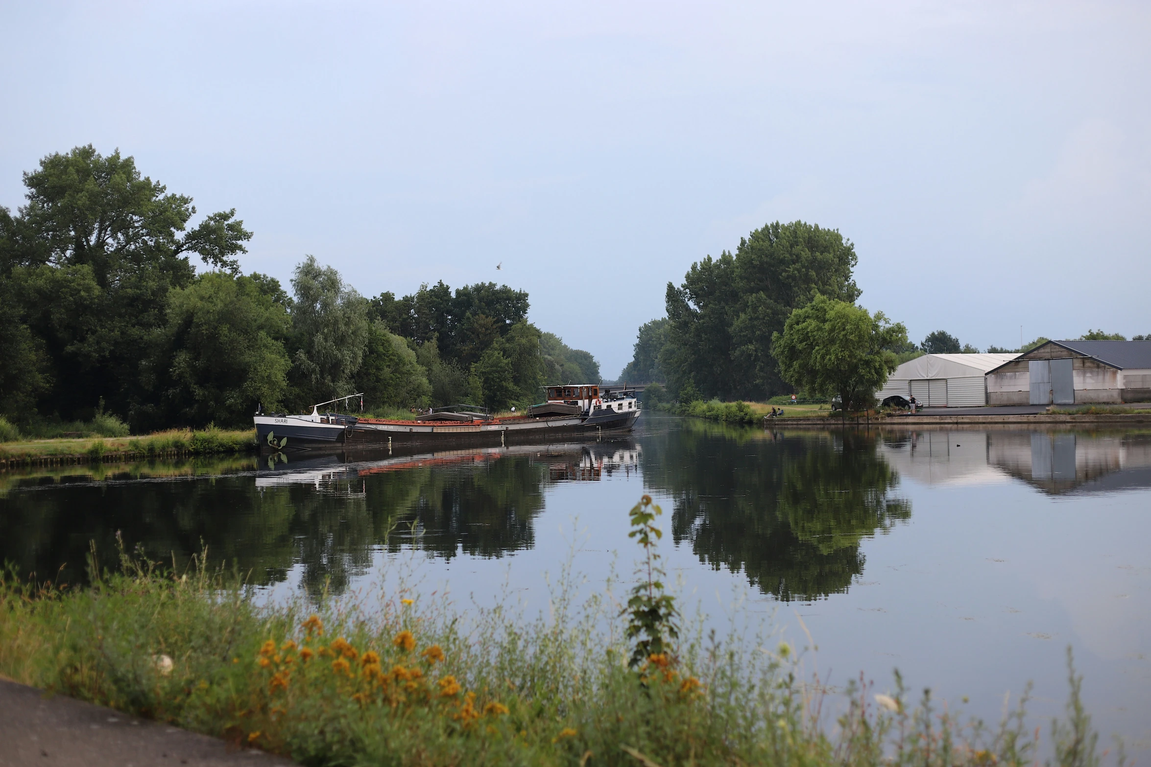 two boats on the side of a lake in the middle of a field