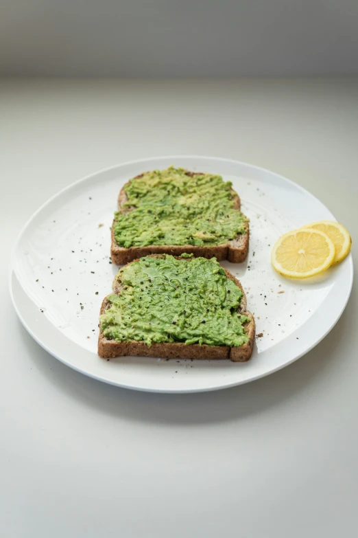 two slices of toast on a white plate with a lemon