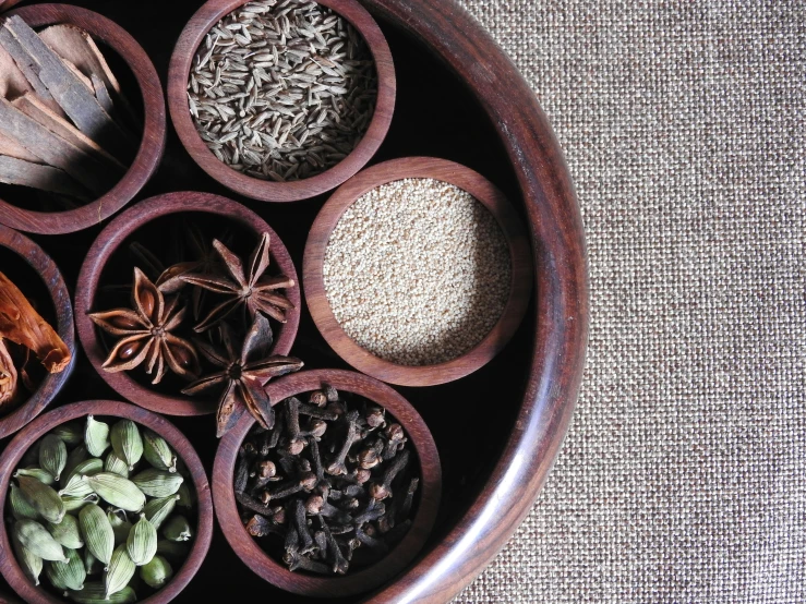 a wooden bowl filled with lots of different types of spices