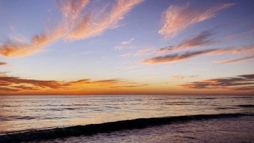 clouds are above the water as sun sets