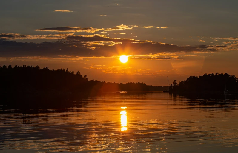 the sun is setting over the trees on the water