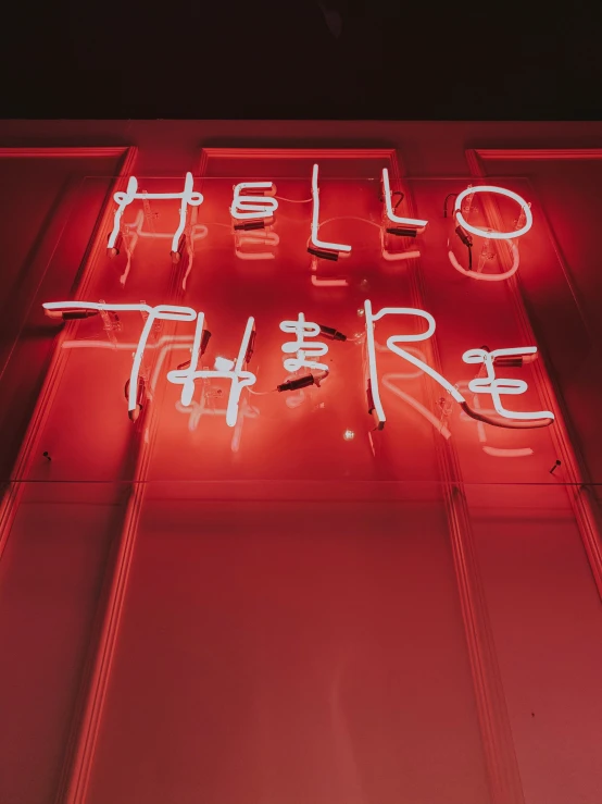 neon sign that says hello there on a building