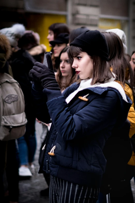 a woman looking at her phone while standing in front of people