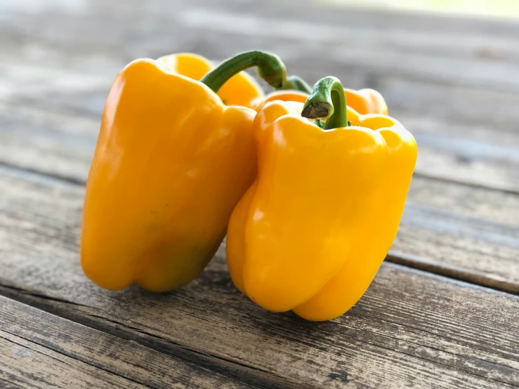 three yellow peppers sitting next to each other on a table