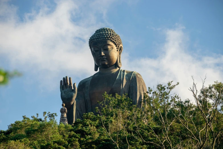 a large statue sitting on top of a lush green hillside