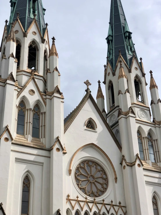 the church has multiple steeples, a large window and a decorative wall