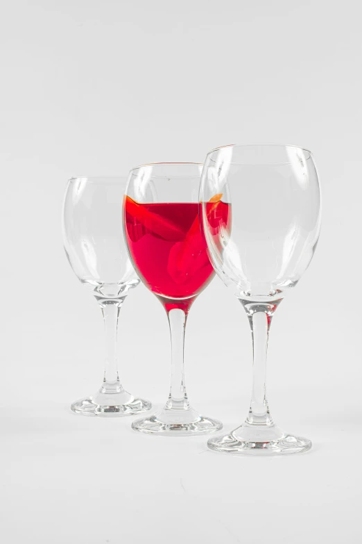 three glasses filled with red wine are lined up