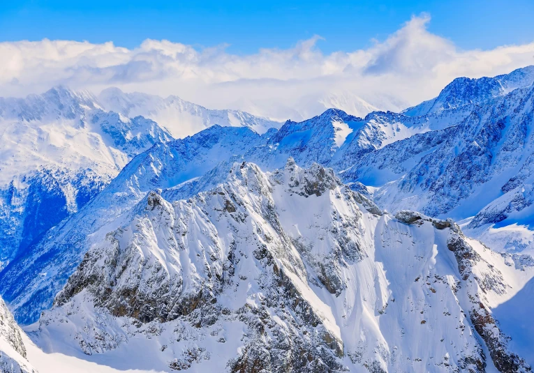 the mountain range covered in snow with blue sky