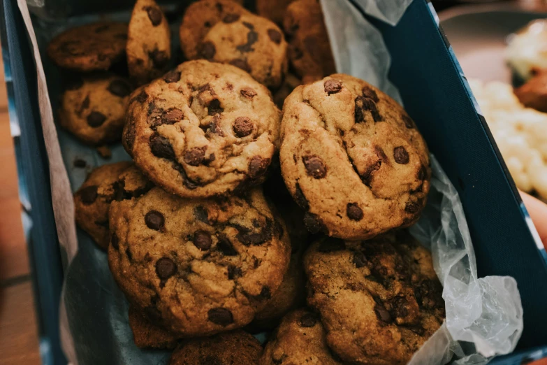 a box of chocolate chip cookies with a hand grabbing one