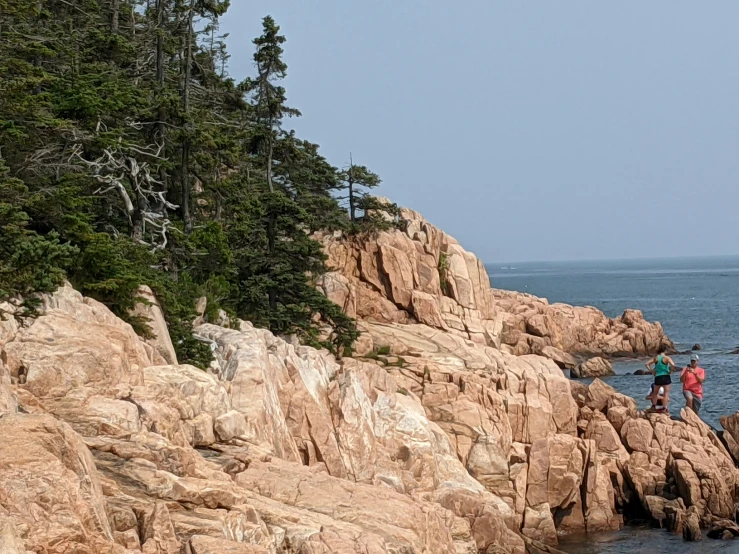 a group of people standing on top of a rocky shoreline