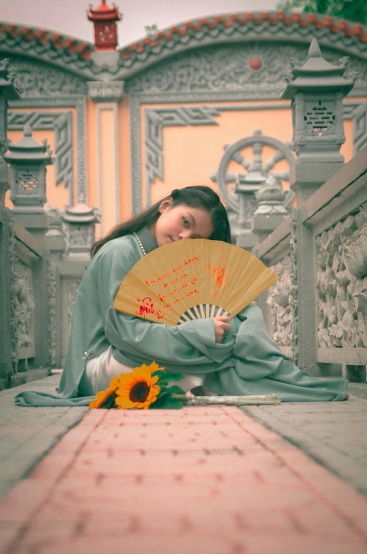 a beautiful woman with a fan sitting on the ground