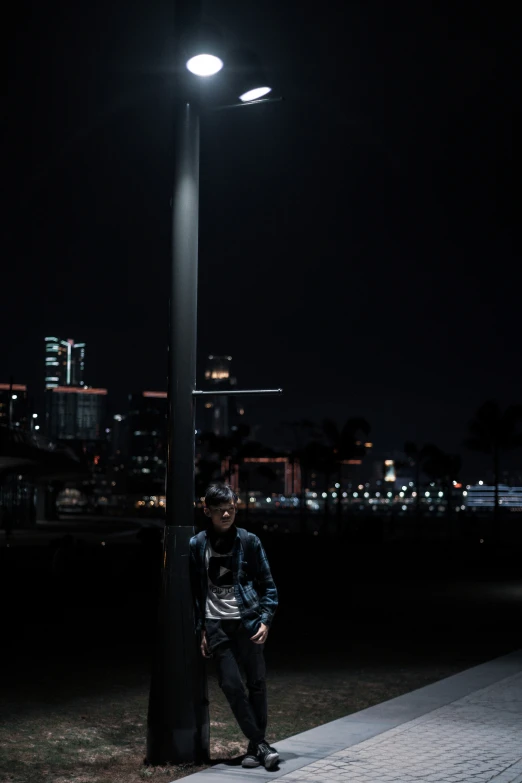 a man leaning against a pole on the street