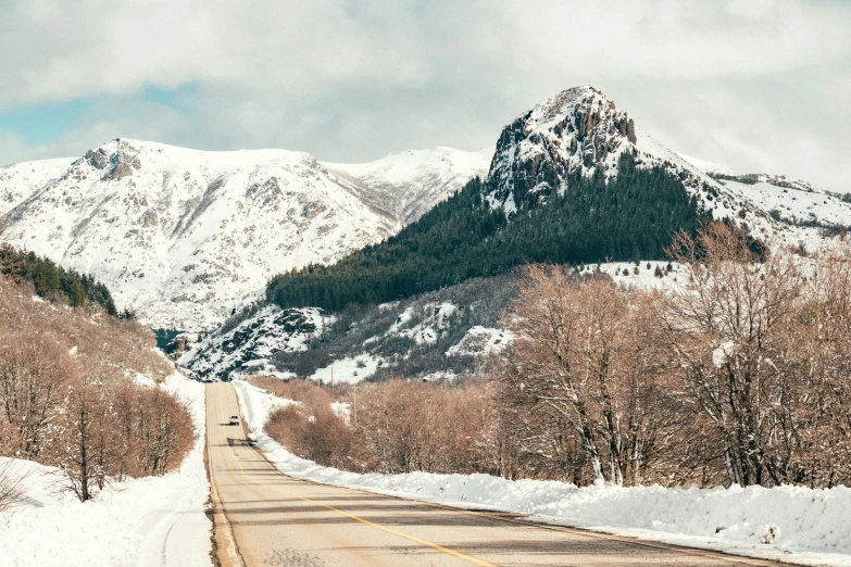 an open road with a snowy mountain in the background