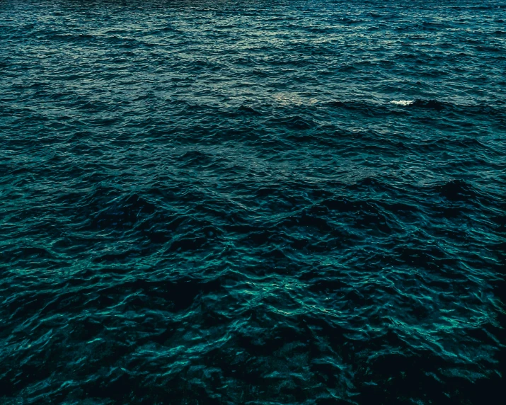 large yacht floating away from camera in dark blue sea