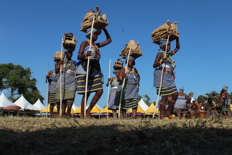 five people with baskets standing on poles near tents