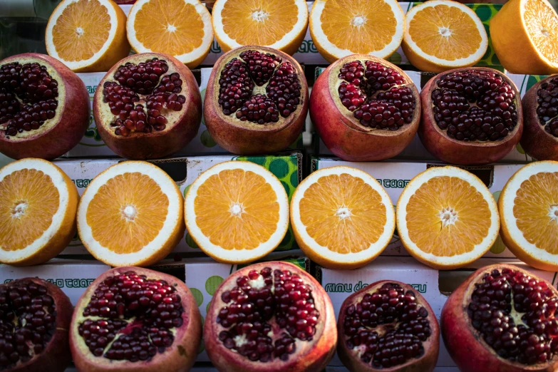 oranges and pomegranates sit together in piles on display