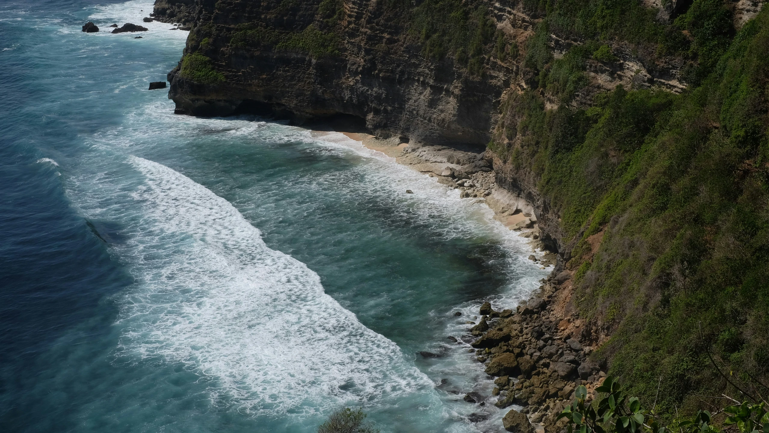 a cliff next to the ocean with large waves