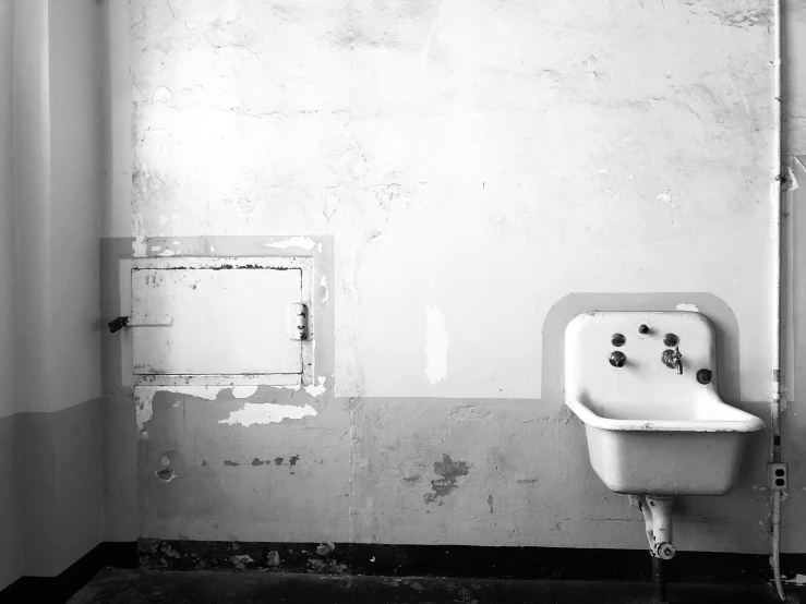 a dirty white bathroom with a sink and door