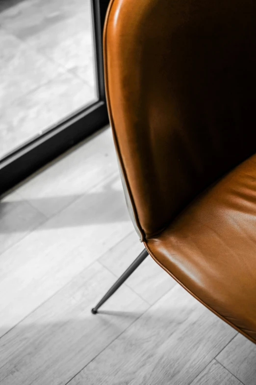 a brown chair next to the window looking at the floor