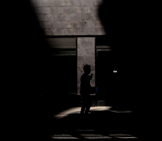 silhouetted person in the shadows of a building and a window