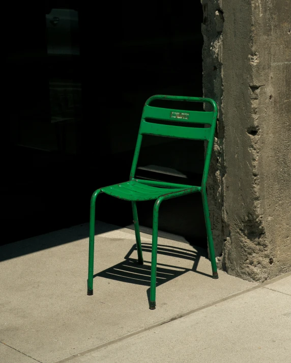 the green chair is beside a cement wall